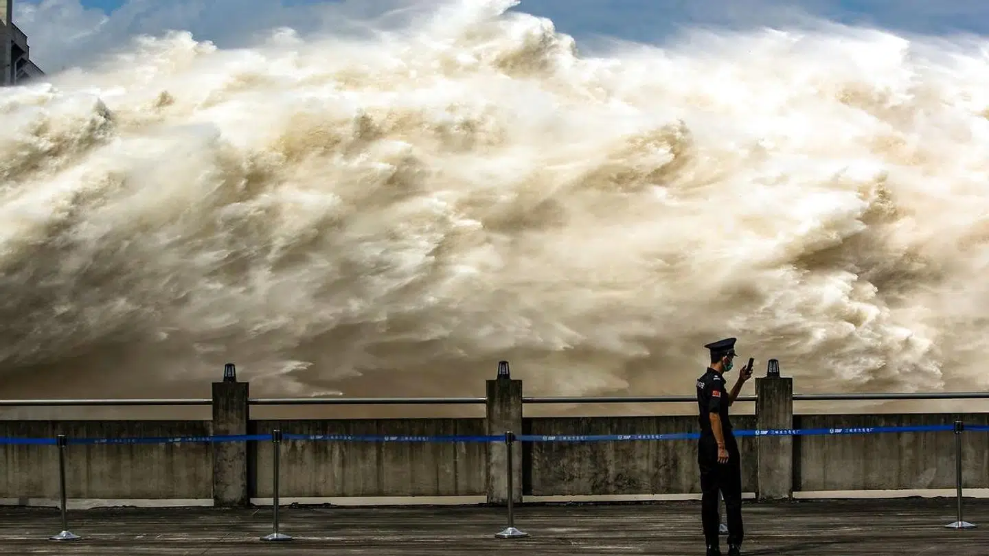 En betjent står foran de voldsomme vandmasser, der lukkes ud gennem sluserne i den enorme De Tre Kløfters Dæmning i Kina.
