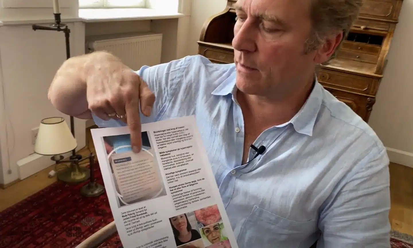 Mads Palsvig viser en flyer frem, om hvorfor mundbind ikke virker med skræmmebilleder af opsvulmede ansigter