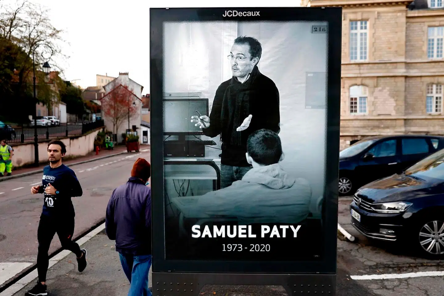 Samuel Paty mindes med plakater overalt i byen, hvor han de sidste tre år af sit liv arbejdede – Conflans-Sainte-Honorine – der ligger 30 kilometer nordvest for Paris. På plakaten ses han i sit es, i gang med at undervise, forklare og debattere. Mordet på læreren er et angreb på rygraden i den franske republik, mener Manuel Valls: det offentlige skolesystem.