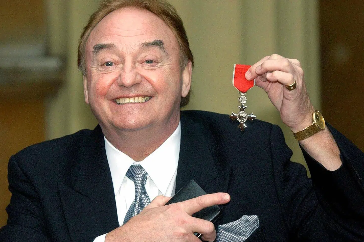 Gerry Marsden viser den orden frem, han modtog fra det britiske kongehus i 2003 for sit velgørende arbejde i hjembyen Liverpool. (Arkivfoto) Matthew Fearn/Ritzau Scanpix