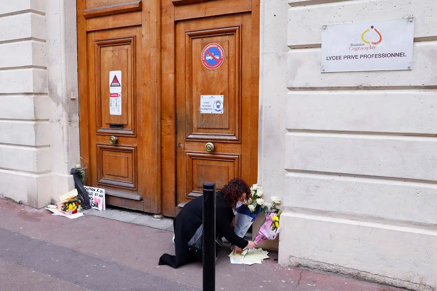 En kvinde lægger blomster uden for den pæne privatskole i Paris-forstaden Argenteuil, hvor 14-årige Alisha og hendes mordere gik i samme klasse.