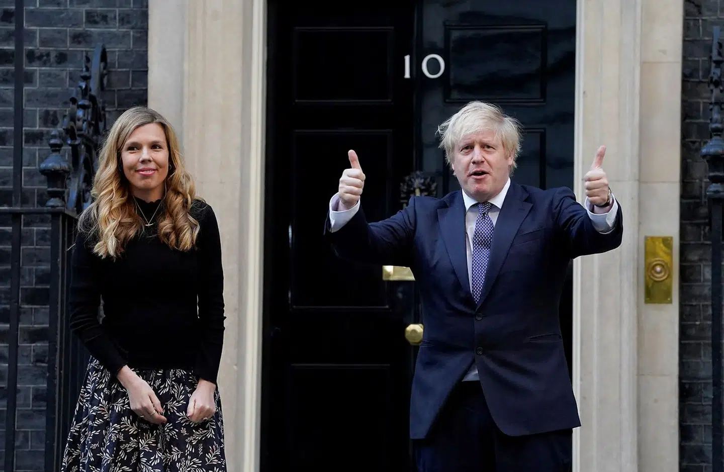 En glad Boris Johnson efter et pressemæde på Downing Street. Ved siden af ham står Carrie Symonds.