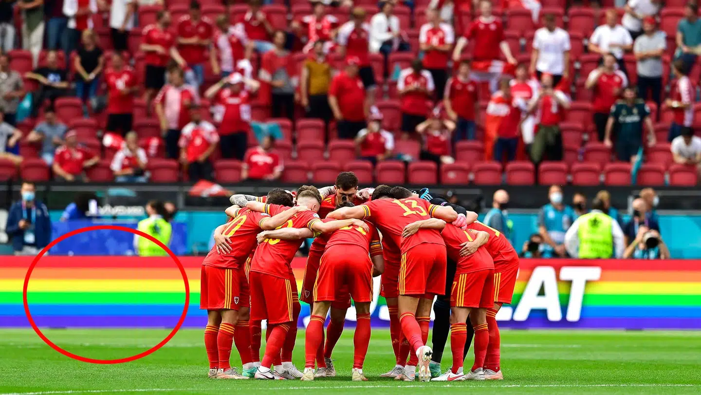 Det walisiske landshold foran en bandereklame med Justeat, der benytter sig af regnbuefarverne.