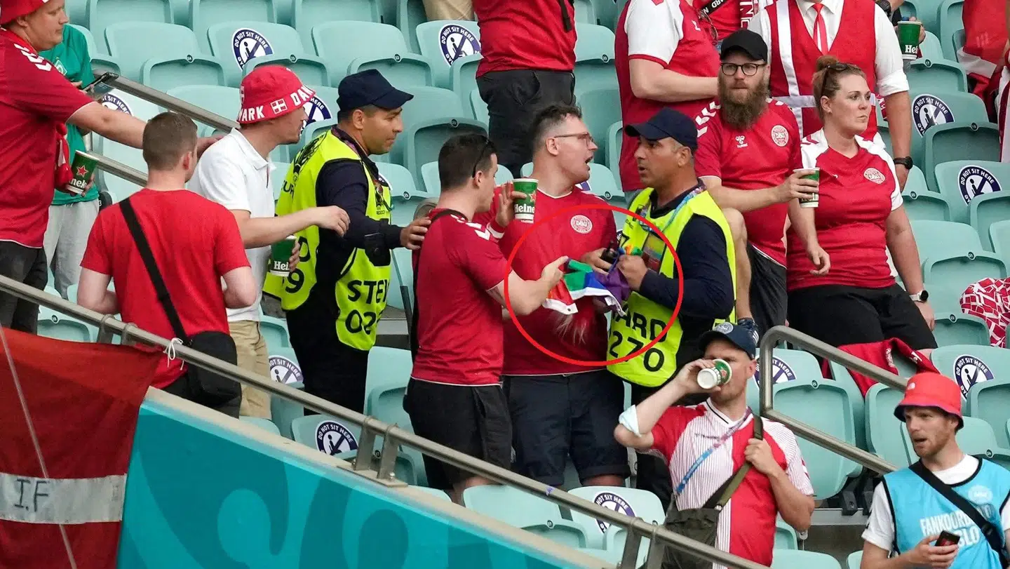 En steward på stadion i Baku ser ud til at konfiskere et regnbueflag fra danske fans.