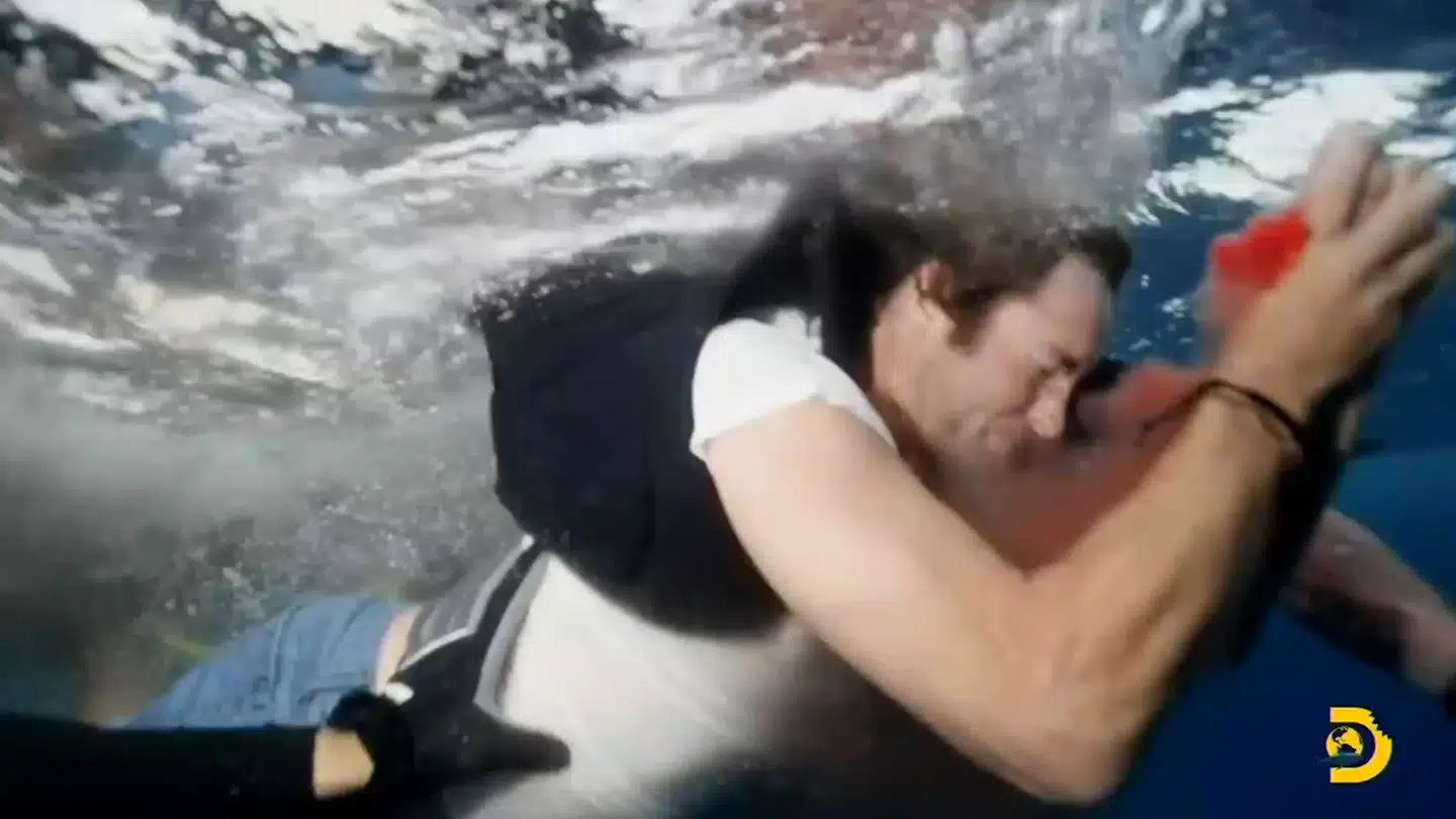 Sean McInerney bløder voldsomt fra hånden, da dykkerne hjulper ham væk fra hajerne og tilbage ombord på produktionens båd.