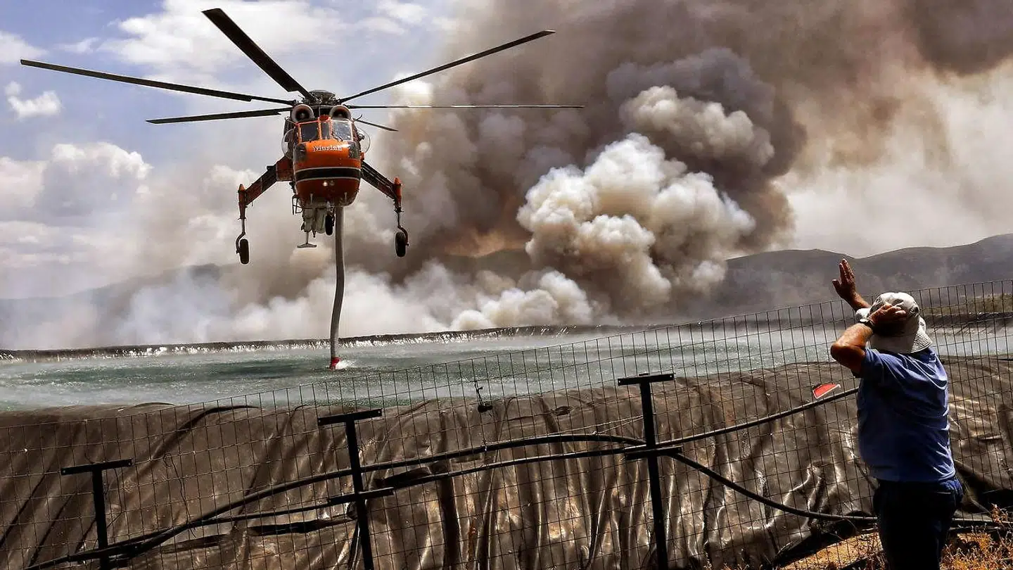 En helikoptor super vand op fra havet, for at sprøjte det ud over skovbranden.