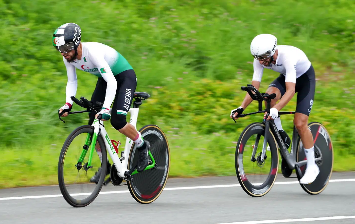 epa09372646 Azzedine Lagab (L) of Algeria and Ahmad Badreddin Wais of the Olympic Refugee Team compete in the Men's Road Cycling Time Trial at the Tokyo 2020 Olympic Games at the Fuji International Speedway in Oyama, Japan, 28 July 2021. EPA/CHRISTOPHER JUE