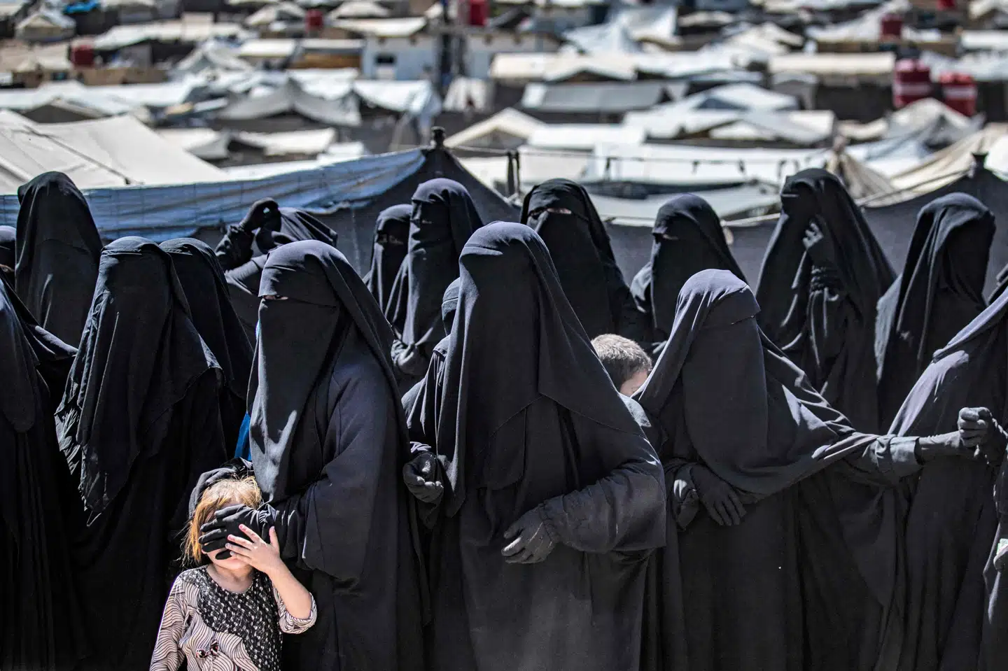 En gruppe kvinder og et enkelt barn står i kø i den berygtede al-Hol lejr i det nordlige Syrien for at modtage hjælpepakker. Det kurdiske selvstyre, der kontrollerer regionen og lejren, har opfordret andre lande til at hente IS-medlemmers koner og børn hjem fra fangelejrene. (Arkivfoto) Delil Souleiman/Ritzau Scanpix