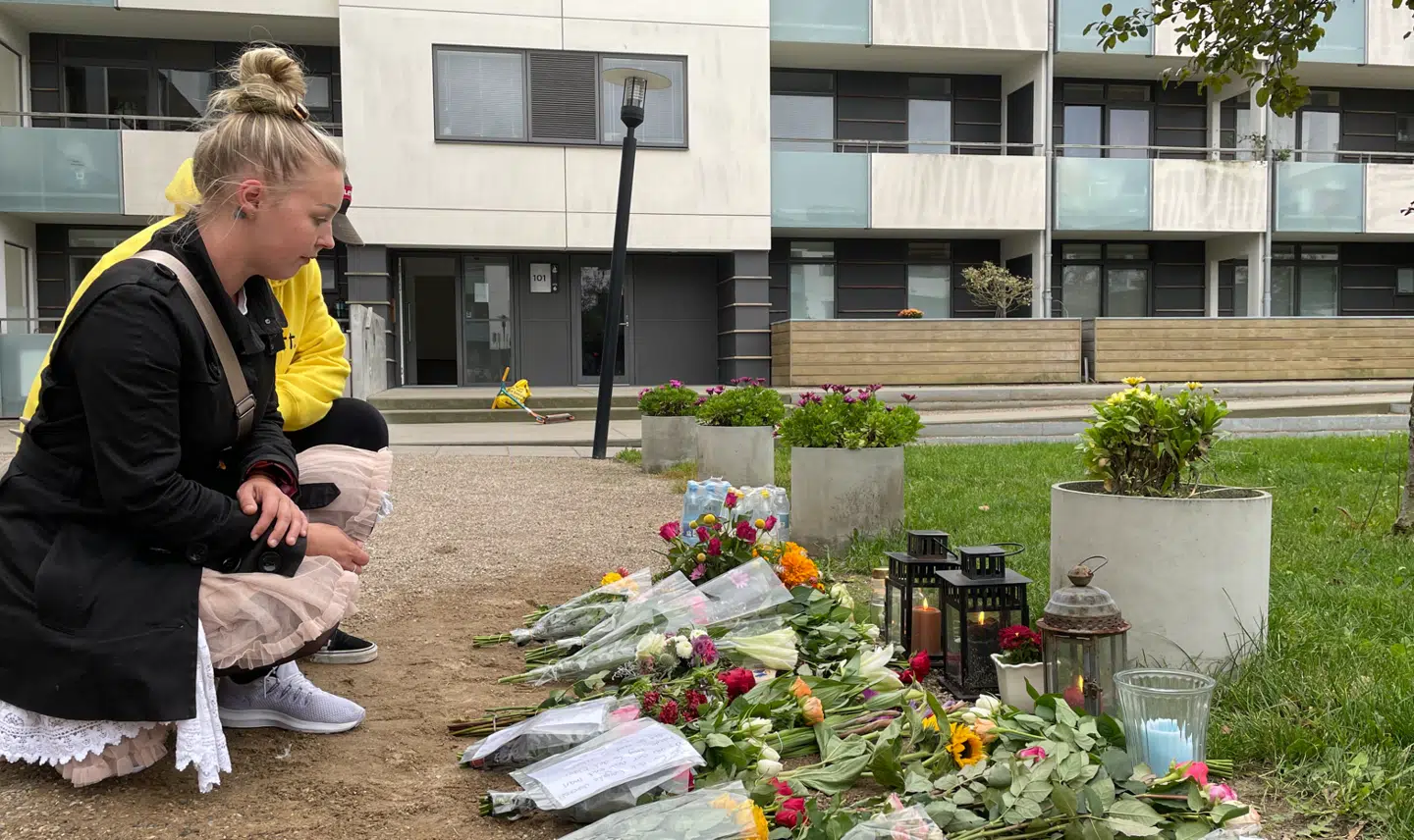 Naboer til den afdøde kvinde lægger blomster.