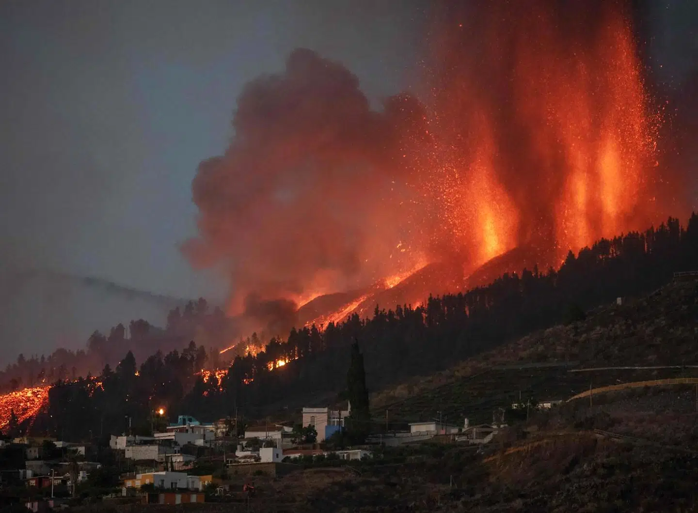 TOPSHOT - Mount Cumbre Vieja erupts in El Paso, spewing out columns of smoke, ash and lava as seen from Los Llanos de Aridane on the Canary island of La Palma on September 19, 2021. - The Cumbre Vieja volcano erupted on Spain's Canary Islands today spewing out lava, ash and a huge column of smoke after days of increased seismic activity, sparking evacuations of people living nearby, authorities said. Cumbre Vieja straddles a ridge in the south of La Palma island and has erupted twice in the 20th century, first in 1949 then again in 1971. (Photo by DESIREE MARTIN / AFP)