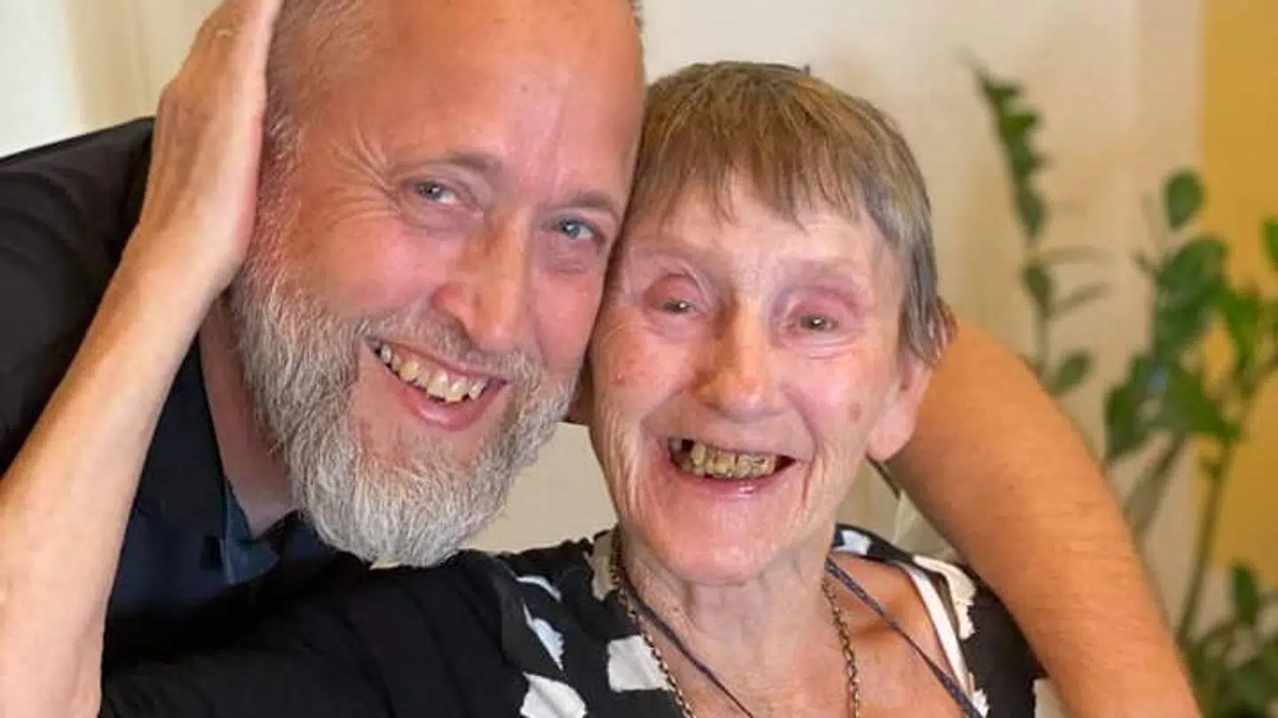 Kenneth Mose Hansen på et plejehjem med en af beboerne, der smiler stort over besøget.