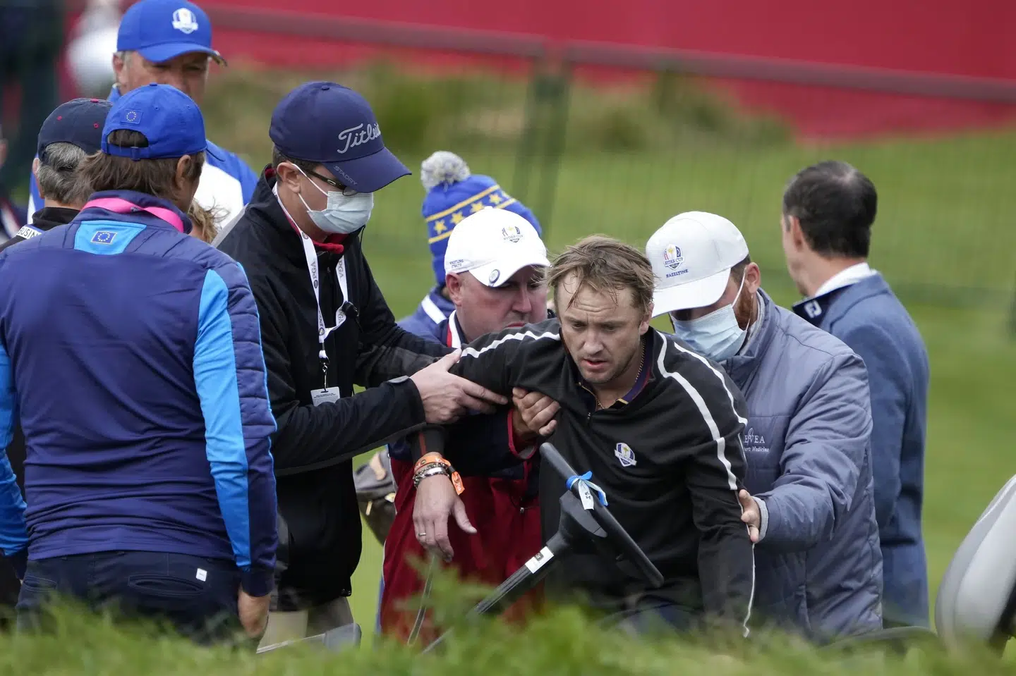 Skuespiller Tom Felton bliver hjulpet på benene efter at være kollapset på 18. hul af golfturnering. Ashley Landis/Ritzau Scanpix