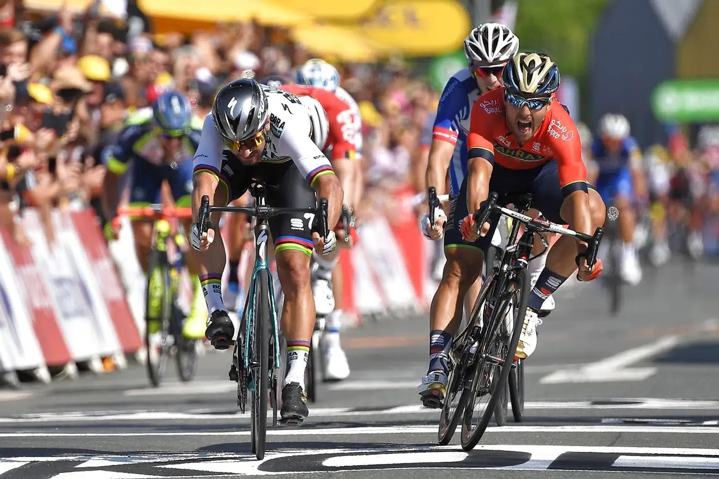 Peter Sagan (L) crosses the finish line ahead of Italy's Sonny Colbrelli (R) and France's Arnaud Demare (Rear) to win the second stage of the 105th edition of the Tour de France cycling race between Mouilleron-Saint-Germain and La Roche-sur-Yon, western France, on July 8, 2018. / AFP PHOTO / Marco BERTORELLO