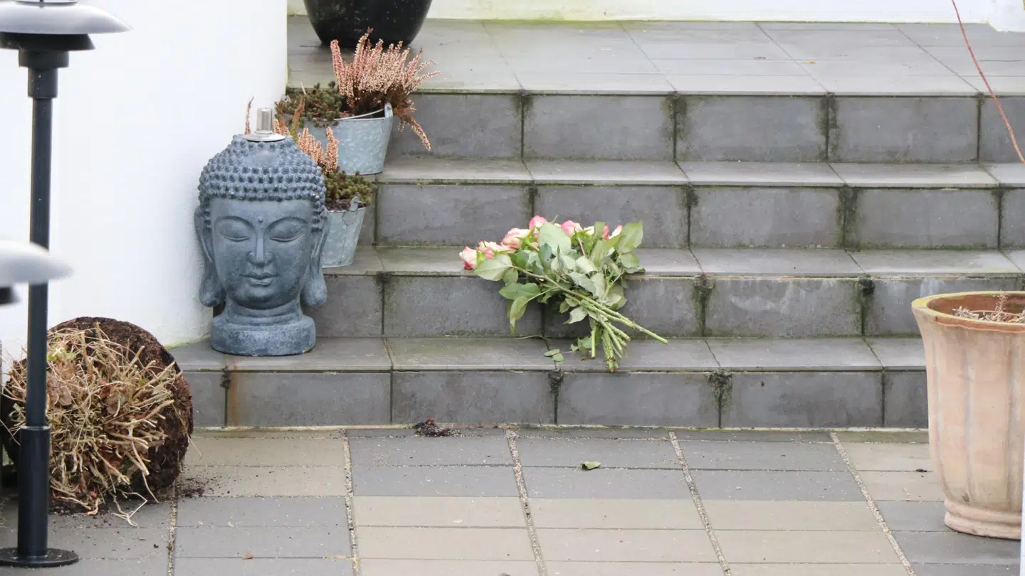 Der er lagt en enkelt buket blomster på hovedtrappen ved huset.