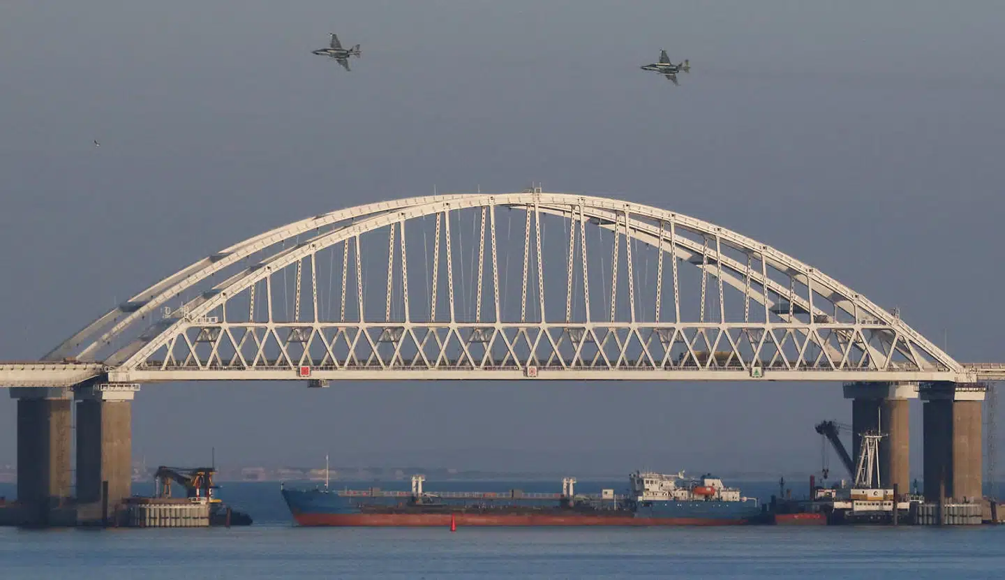 Russiske jagerfly overflyver en bro over Kerch-strædet, som forbinder Sortehavet med Det Azovske Hav. Samtidig blokerer et fragtskib for indsejlingen.