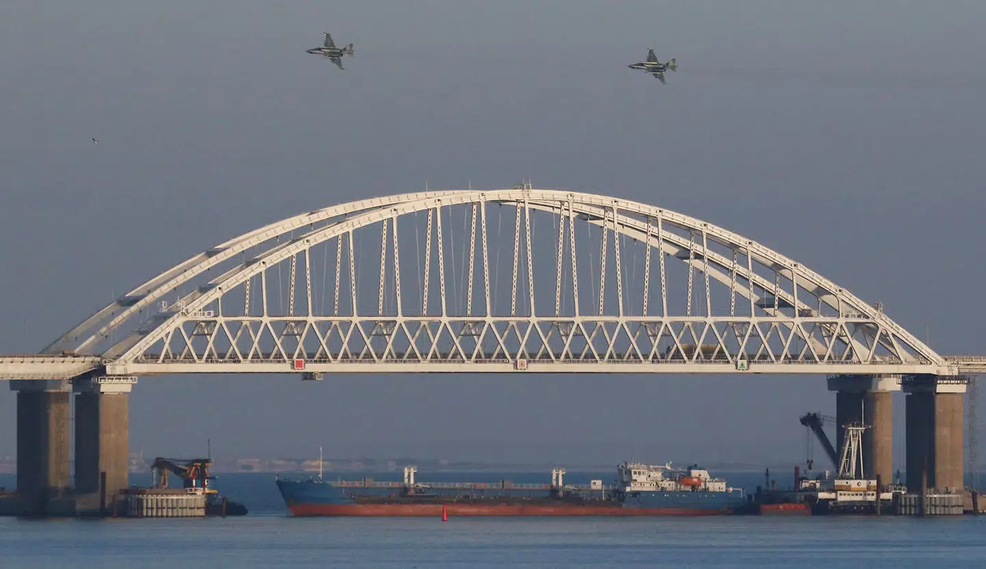 Russiske jagerfly overflyver en bro over Kerch-strædet, som forbinder Sortehavet med Det Azovske Hav. Samtidig blokerer et fragtskib for indsejlingen.
