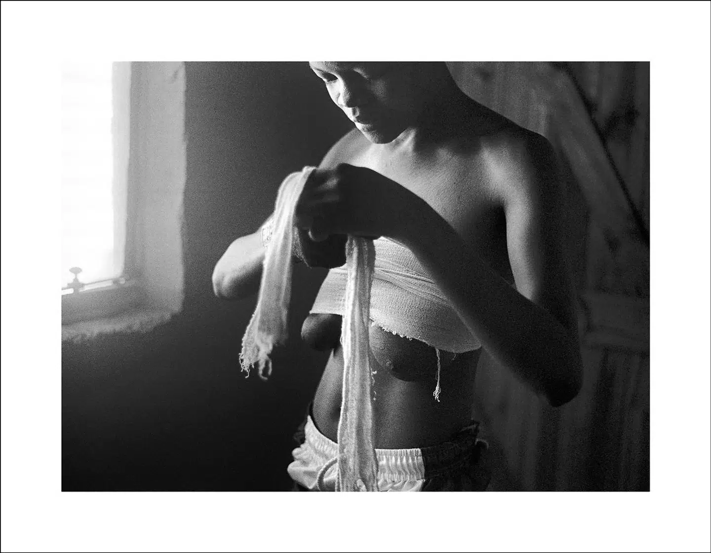 En kvindeskikkelse er ved at vikle sine bryster ind i gaze. Værket er fra »Only Half The Picture«-serien fra 2002-2006.