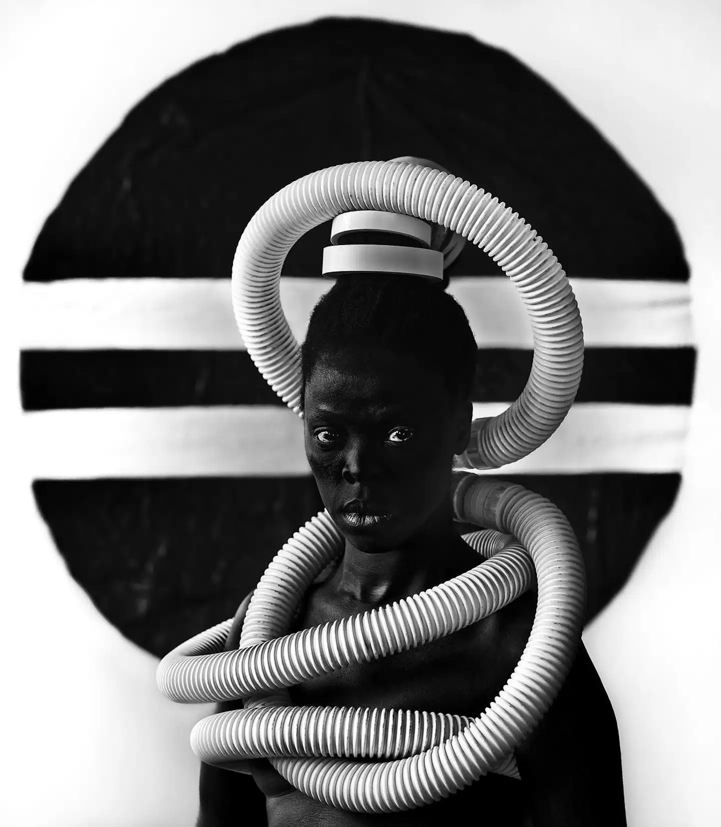 Zanele Muholi med en tørretumblerslange om hovedet. Billedet er en hyldest til kunstnerens mors husarbejde for en hvid familie under apartheid: »Sebenzile, Parktown«, 2016.