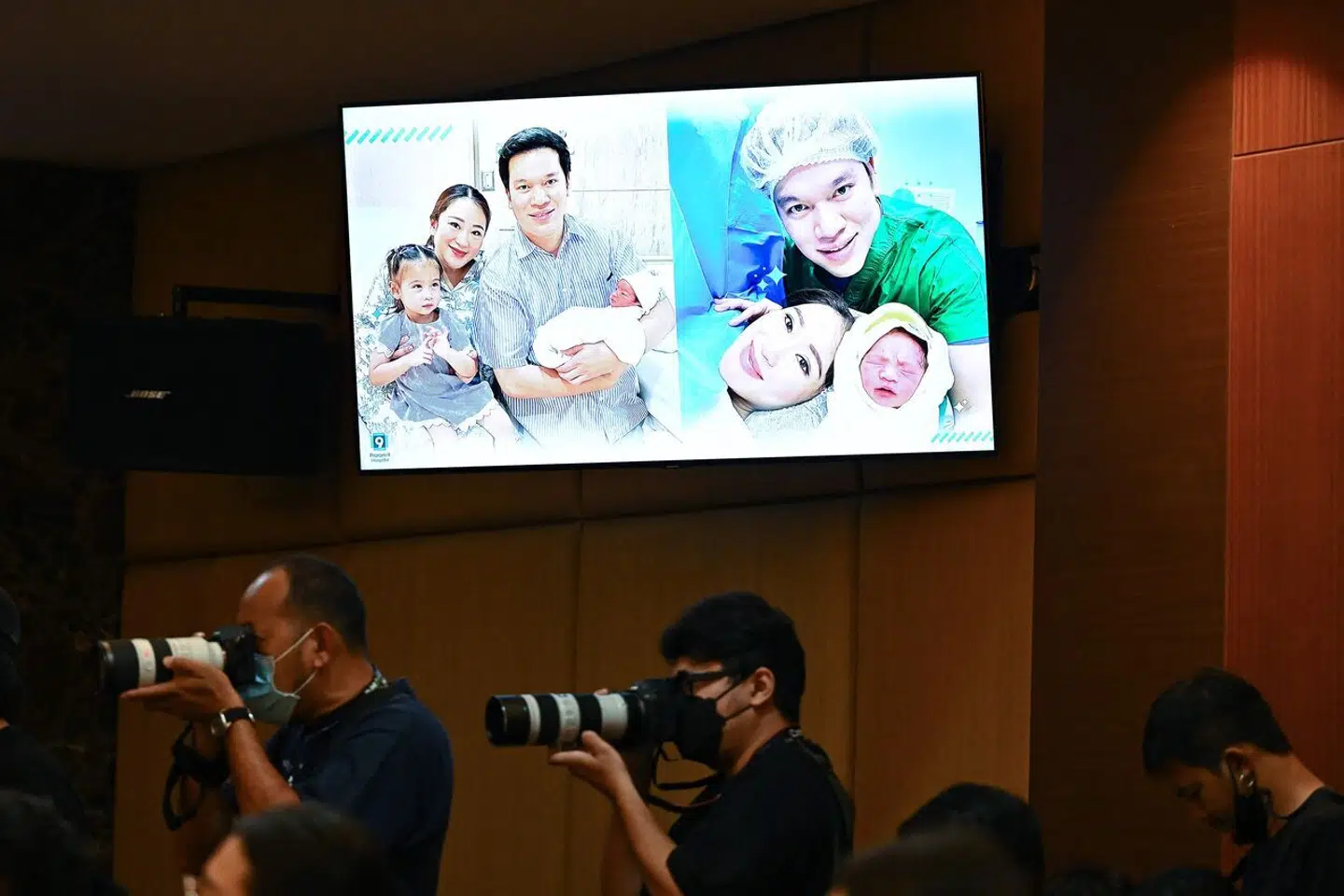 Fotograferne står under et skilt med familiefotos af den nye familie på Praram 9 hospitalet i Bangkok, Thailand, 3. maj.