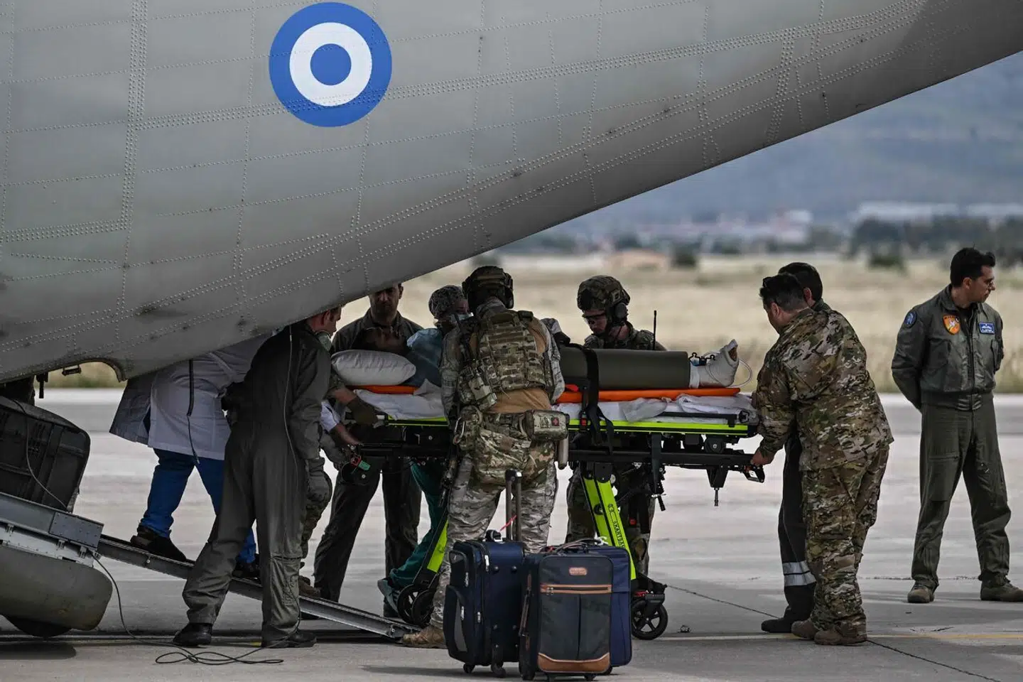 En såret græsk borger bæres ud af et militærfly, efter at det er ankommet fra Sudan til Athen.