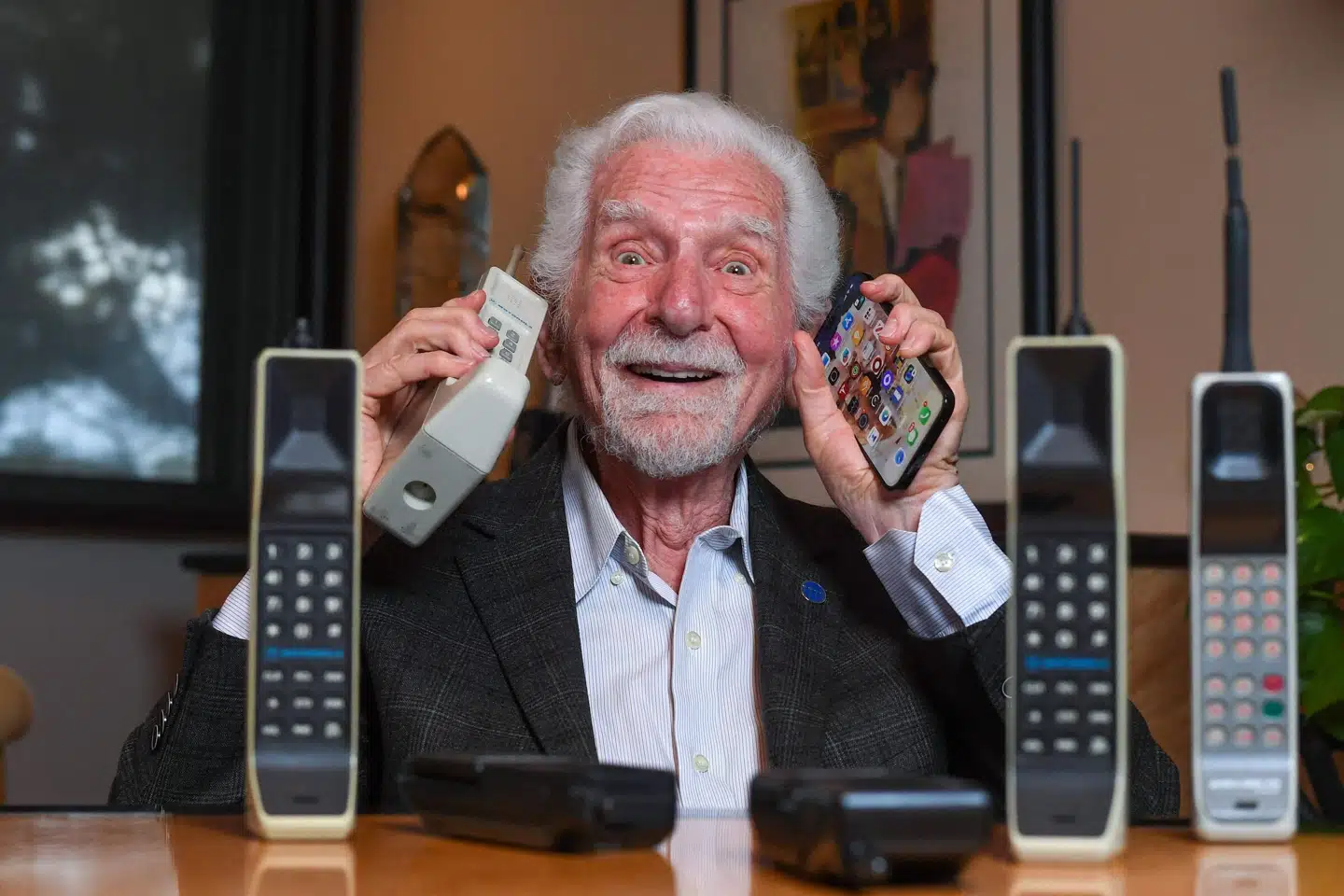 Martin Cooper sidder med en kopi af den første mobiltelefon i sin ene hånd og en iPhone i den anden. Der er sket meget, siden han for 50 år siden foretog det første opkald fra en mobiltelefon. Valerie Macon/Ritzau Scanpix