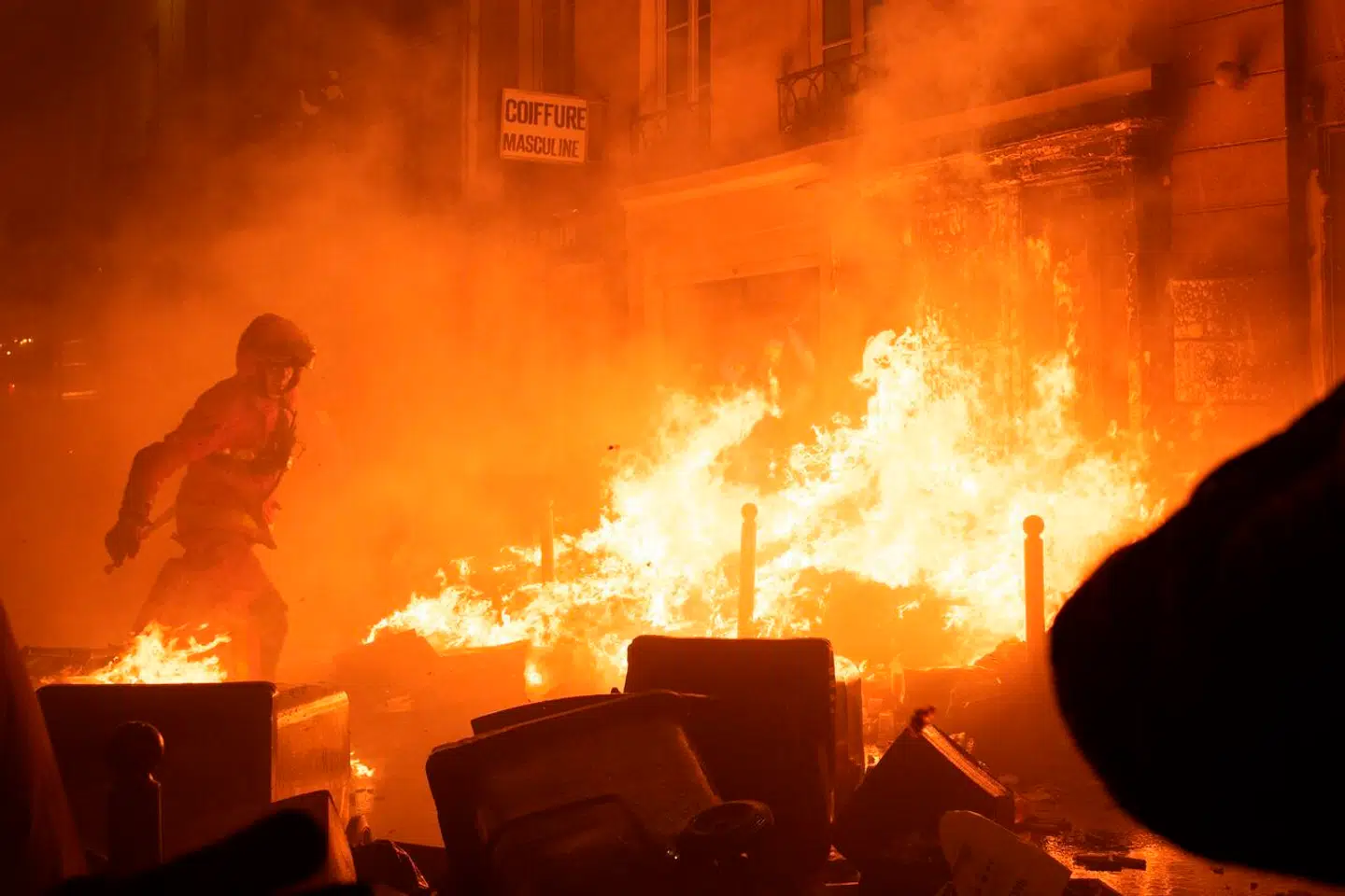 TOPSHOT - A firefighter tries to extinguish a fire during a demonstration, a week after the government pushed a pensions reform through parliament without a vote, using the article 49.3 of the constitution, in Paris on March 23, 2023. - Some 1.089 million protesters took part in demonstrations in France on March 23, 2023, against President Emmanuel Macron's pension reform, the interior ministry said, with 119, 000 marching in Paris alone. (Photo by Anna KURTH / AFP)