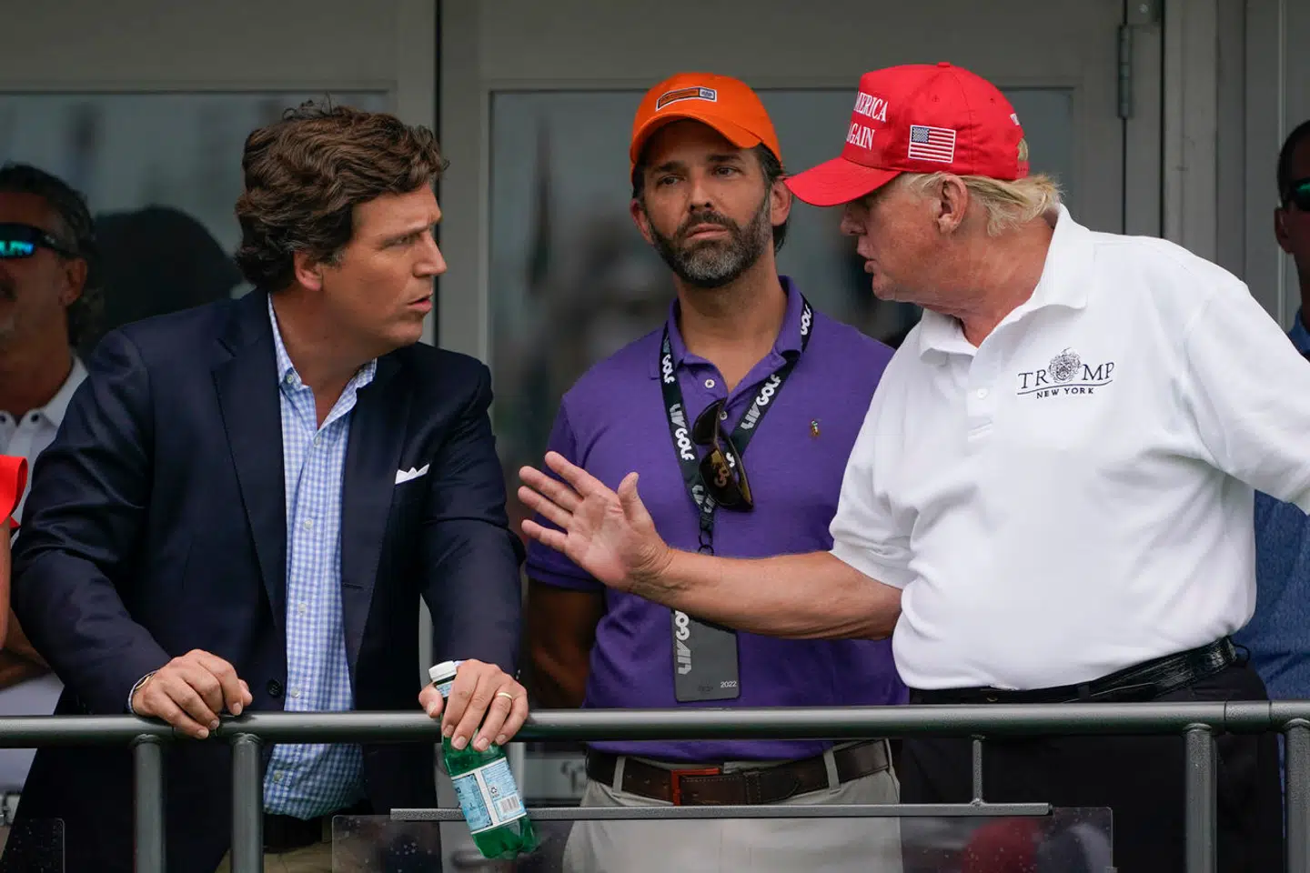 Tucker Carlson i samtale med Donald Trump, mens Donald Trump jr. kigger på.