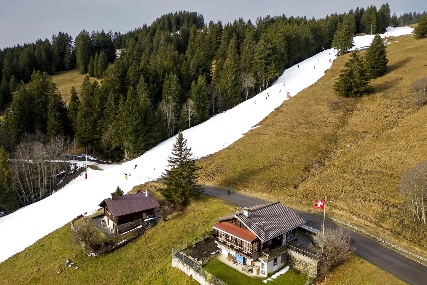 Dronebillederne over Villars-sur-Ollon i Schweiz viser løjpen af kunstig sne midt i det ellers grønne landskab.