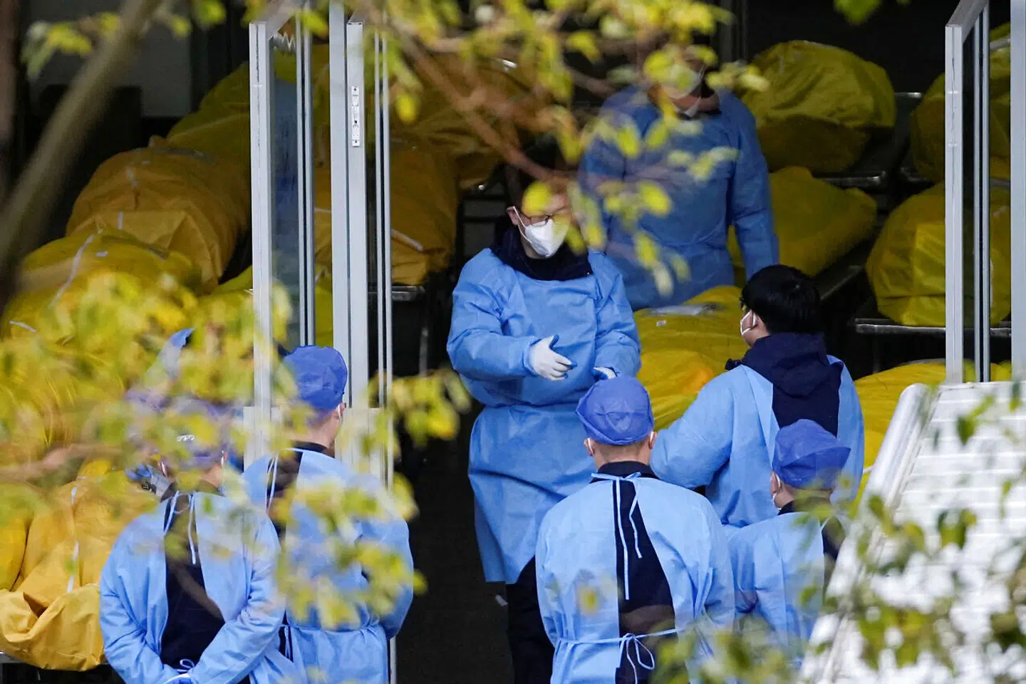 Ansatte står mellem døde i ligposer på et hospital i Shanghai. Det vides ikke præcis, hvor mange der hver dag dør i Kinas akutte covid-udbrud.