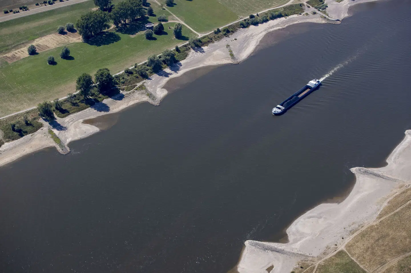 Et skib uden ret megen last bevæger sig frem på Rhinen mellem Köln og Düsseldorf. Skibstrafikken er alvorlig ramt af tørken og den lave vandstand i floden, der er en Tysklands vigtigste handelsruter. Christoph Reichwein/Ritzau Scanpix