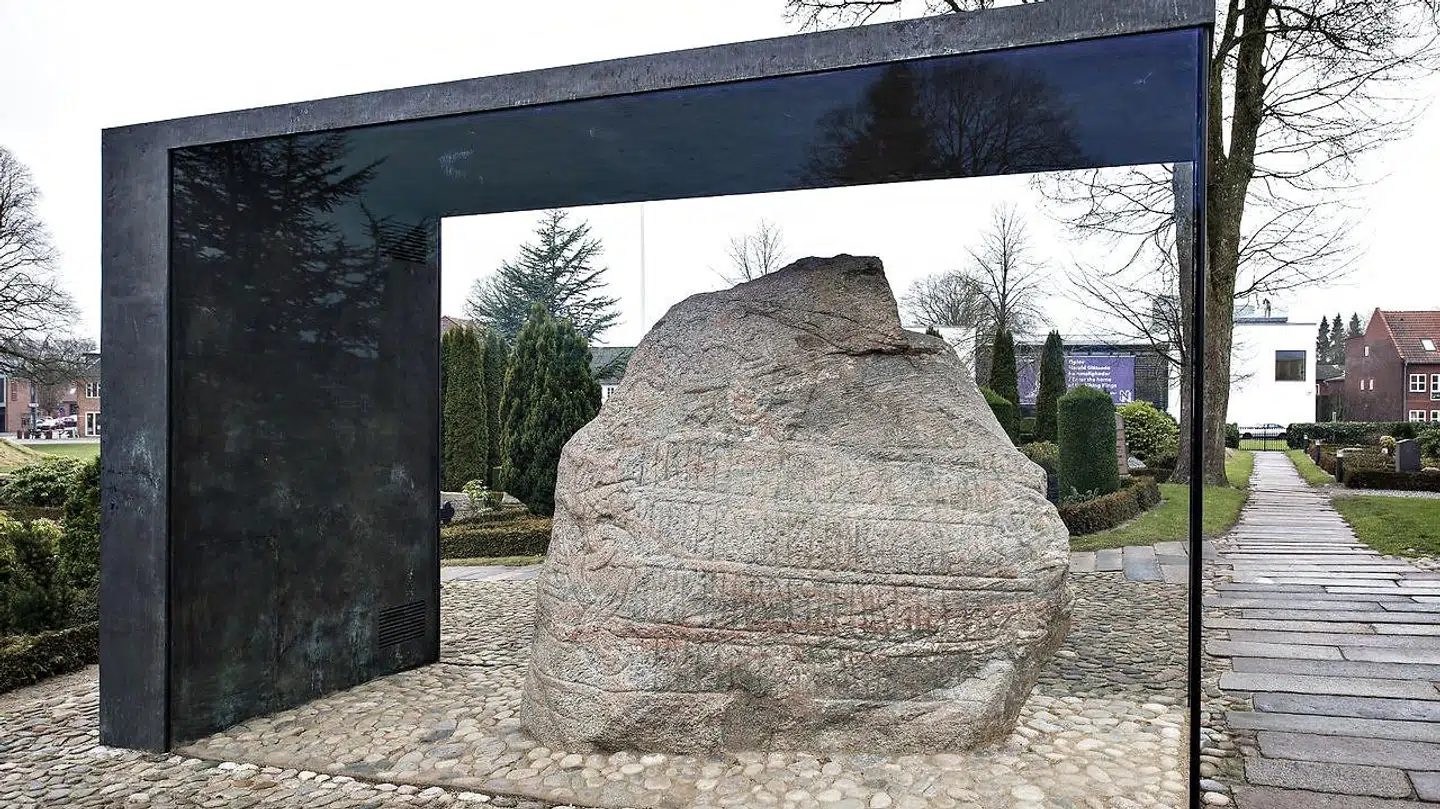 Jellingstenene i Jelling, de to runesten i Jelling. Er placeret ved Jelling Kirke, afspejler overgangen fra den hedenske vikingetid til den kristne middelalder. Den mindste runesten er fra cirka år 935, rejst af Gorm den Gamle. Den store runesten er rejst af Harald Blåtand. Her ses den store runesten.