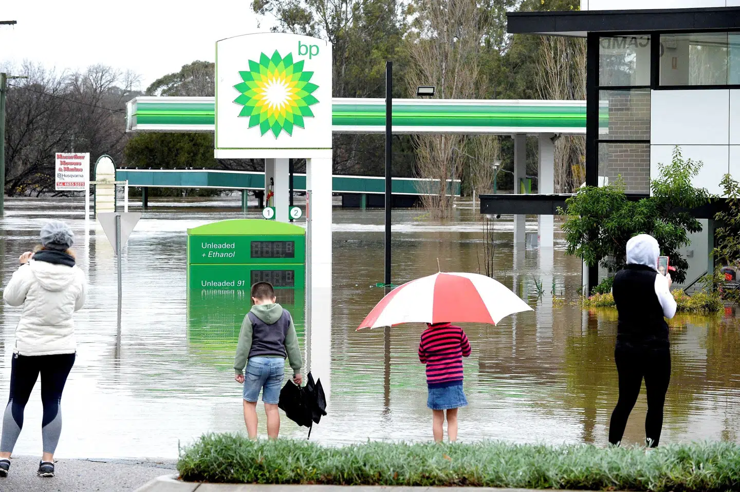 Australiere overværer en oversvømmet tankstation i Camden, som er en forstad til Sydney. Muhammad Farooq/Ritzau Scanpix
