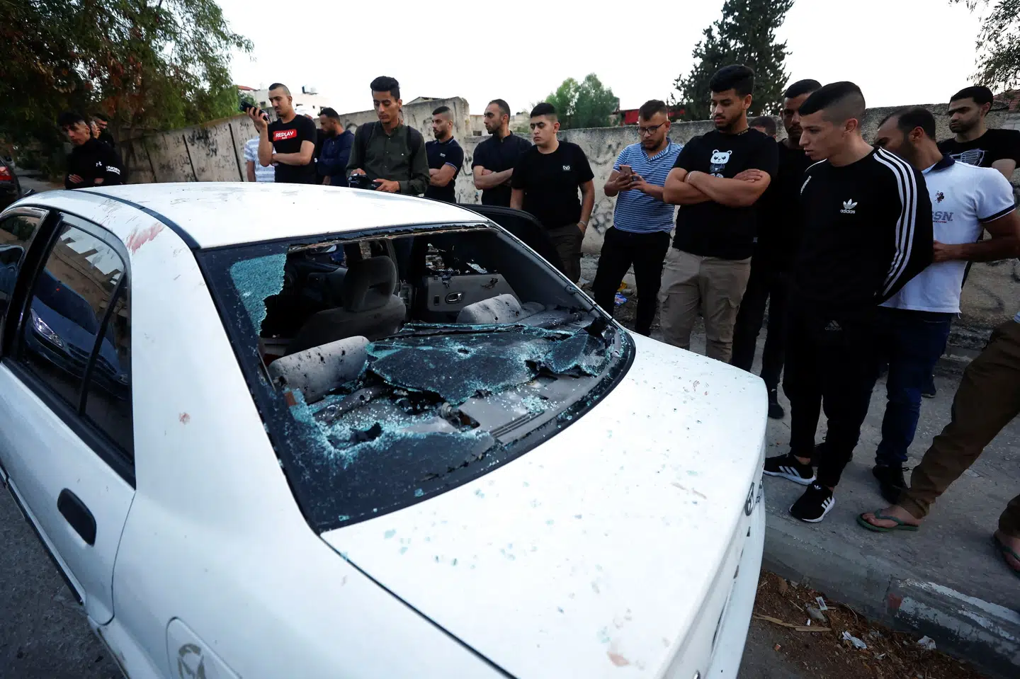 Beboere ser til en gennemhullet bil på Vestbredden, efter at tre palæstinensere er blevet skudt og dræbt af israelske styrker fredag. Mohamad Torokman/Reuters
