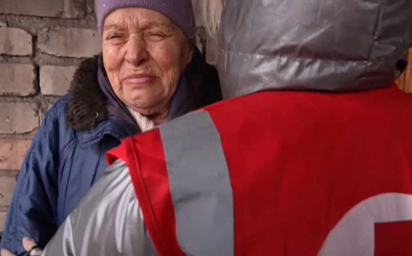 En kvinde står og græder, mens hun trøstes af frivillig fra Røde Kors. Foto: Screenshot af videoen fra AP.