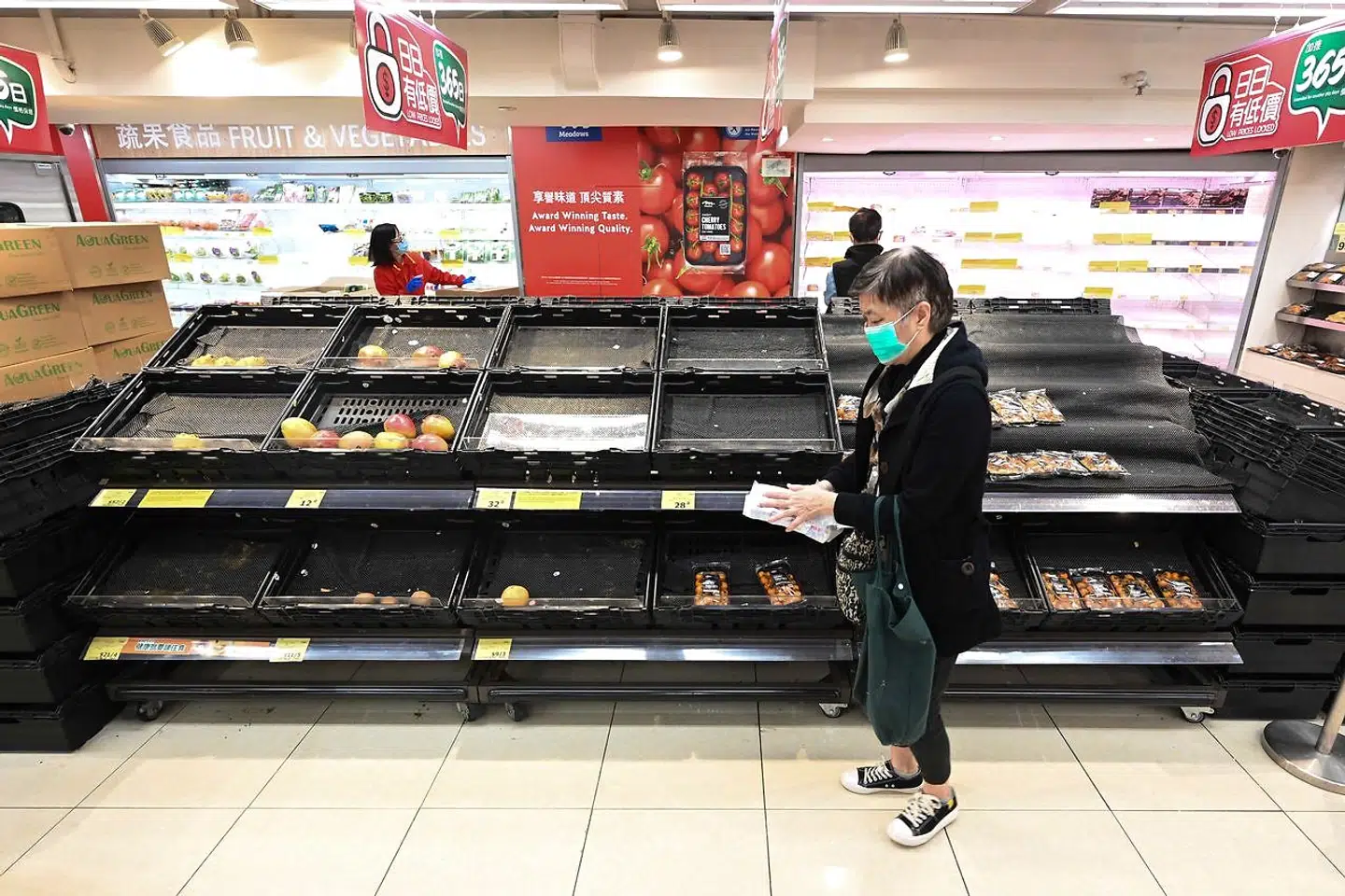 Kunden står ud for nogle hylder, der er tomme i et supermarked i Hongkong.