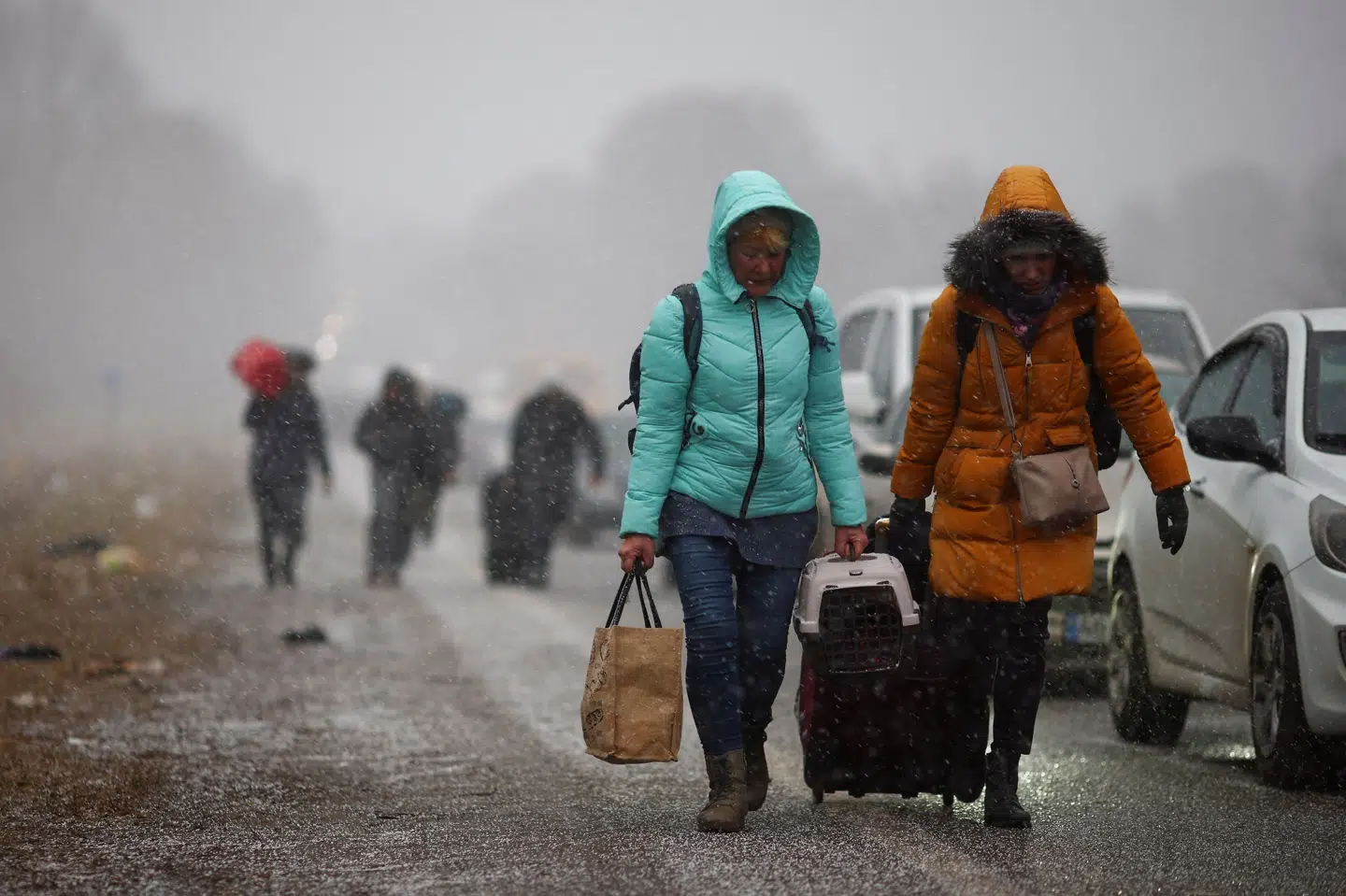Ukrainere på flugt fra de russiske angreb går til fods mod en grænseovergang til Polen, forbi de lange rækker af biler, der holder i kø for at krydse grænsen ind i Polen. Thomas Peter/Reuters