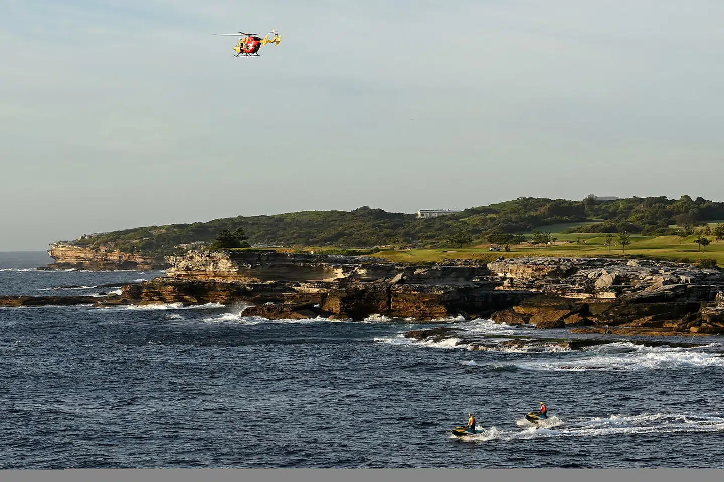 En redningshelikopter og to jetski afsøger vandet ved Little Bay Beach i Sydney, Australien.