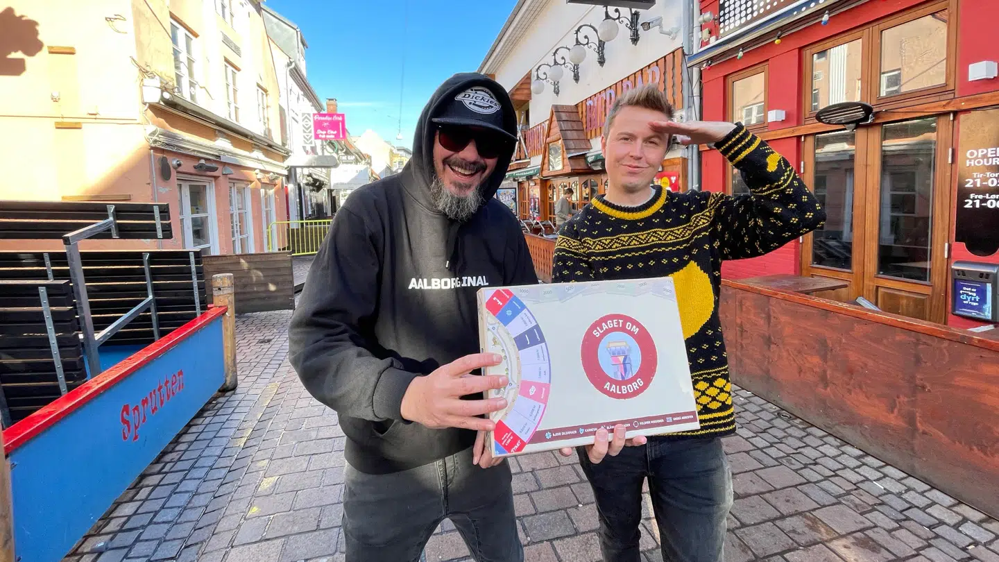 Byens urbane borgmester Jonny Hefty, der pryder en del af valutaen i spillet, sammen med spilmager Sune Frandsen i 'Gaden*.