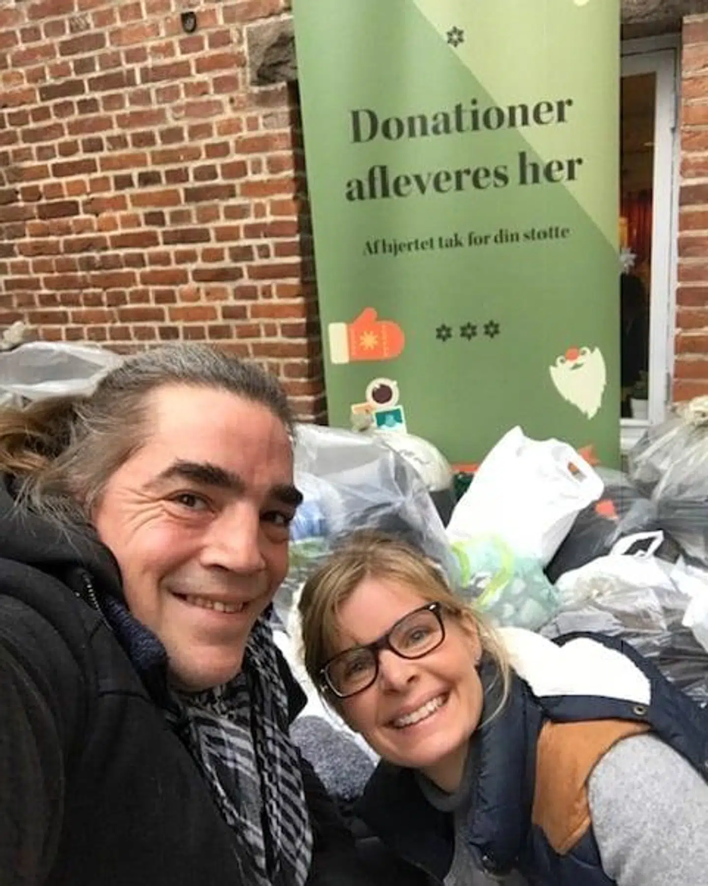 Folk plejer at være rigtig søde til at komme med ting, når Rikke Dam Brøndum Sejthen holder den årlige indsamling. Her er et billede fra december 2019, hvor Rikke står sammen med en af de tidligere hjemløse, som nu er frivillig i organisationen. Bag ved dem er der en masse poser med tøj, som folk er kommet med. Foto: Hjemløs i Aarhus.