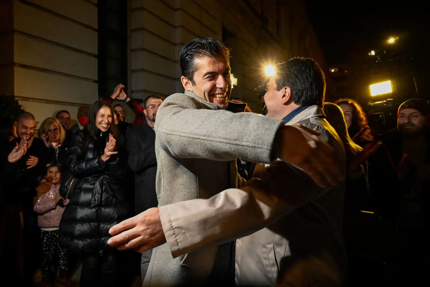 Kiril Petkov (i midten), der tidligere har siddet midlertidigt på posten som økonomiminister i Bulgarien, omfavner Asen Vassilev, tidligere midlertidig finansminister, på valgaftenen søndag. De to har sammen stiftet det nye midterparti, der ifølge den foreløbige optælling ser ud til at blive største efter søndagens parlamentsvalg. Nikolay Doychinov/Ritzau Scanpix