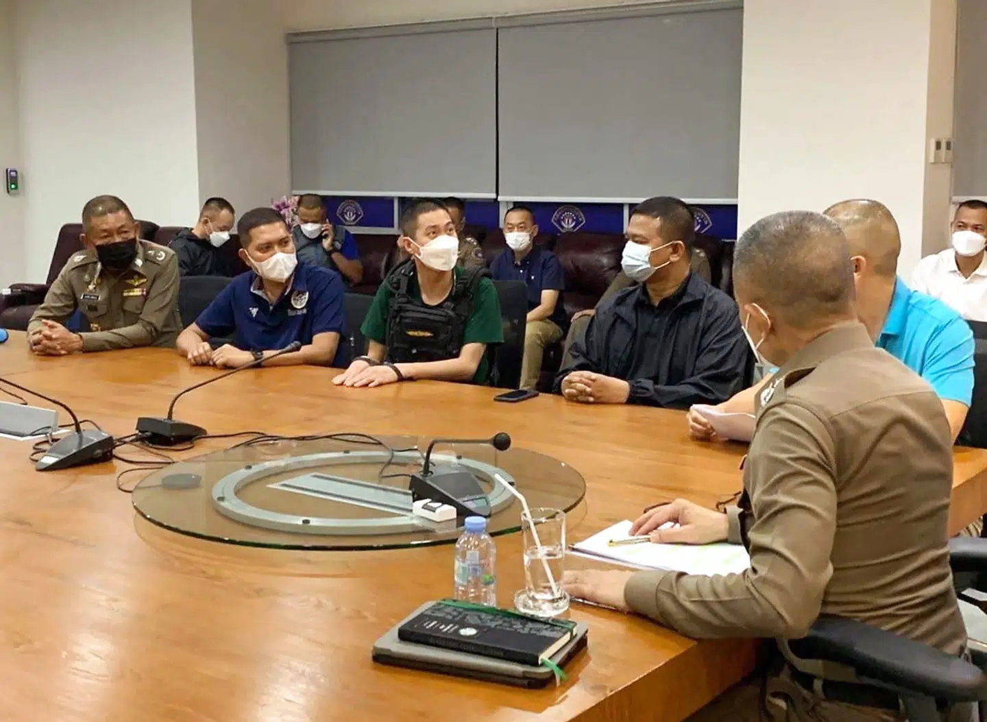 Politichefen Thitisan Utthanaphon (i midten) sidder til bords i Bangkok. Han er nu sigtet for mordet på en 24-årig narkokurer.