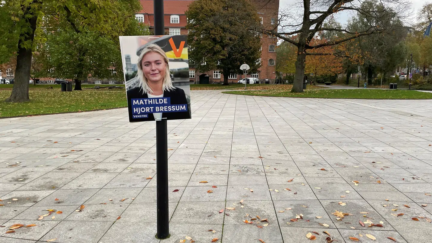 Billedet viser en plakat, der hænger meget under 2,3 m. Billedet er taget ved Mølleparken i Aarhus, og det var ikke det eneste eksempel i parken.
