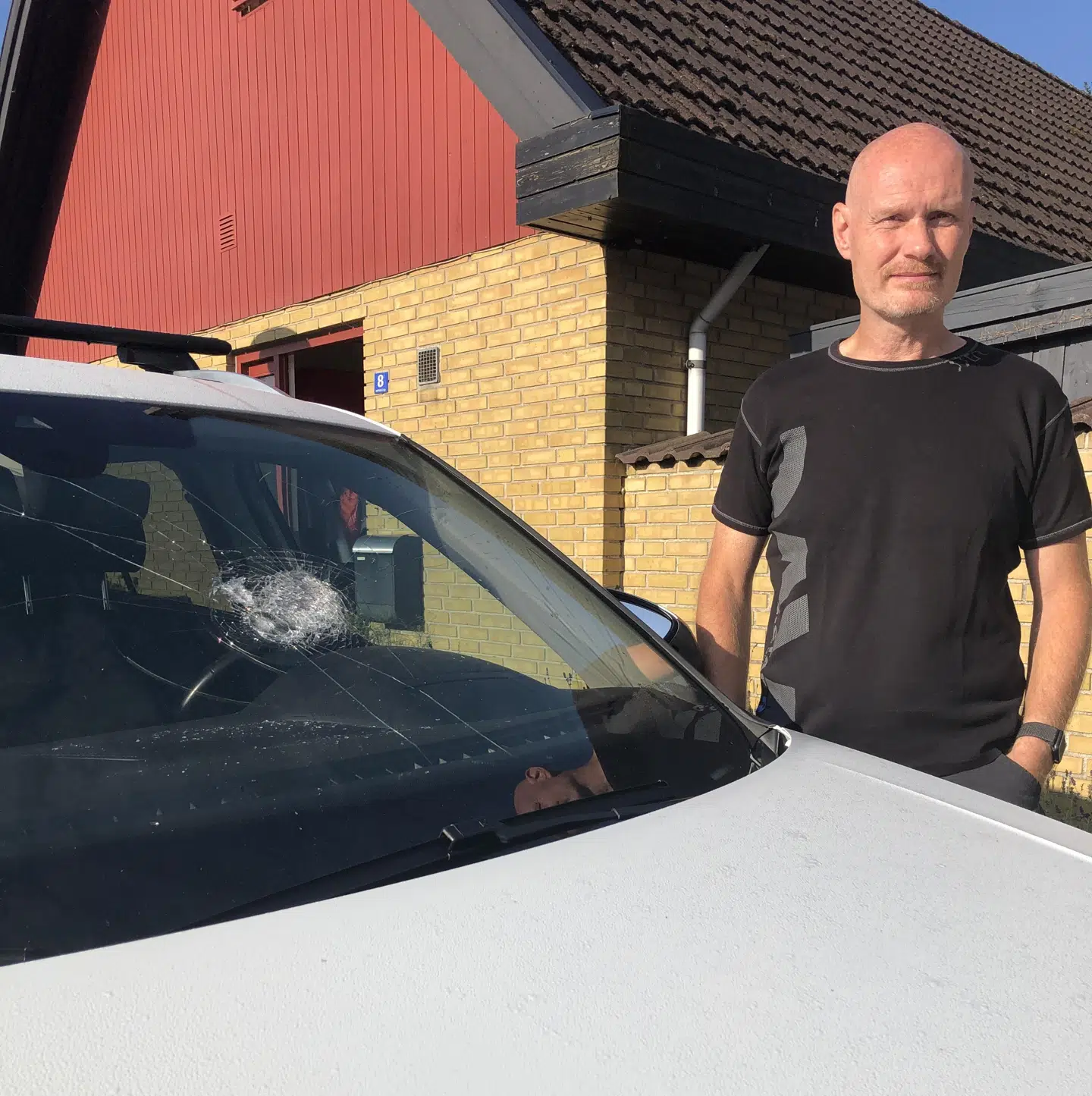 Sten Hagedorn ved sin bil, der har taget tydelig skade af stenkastet.