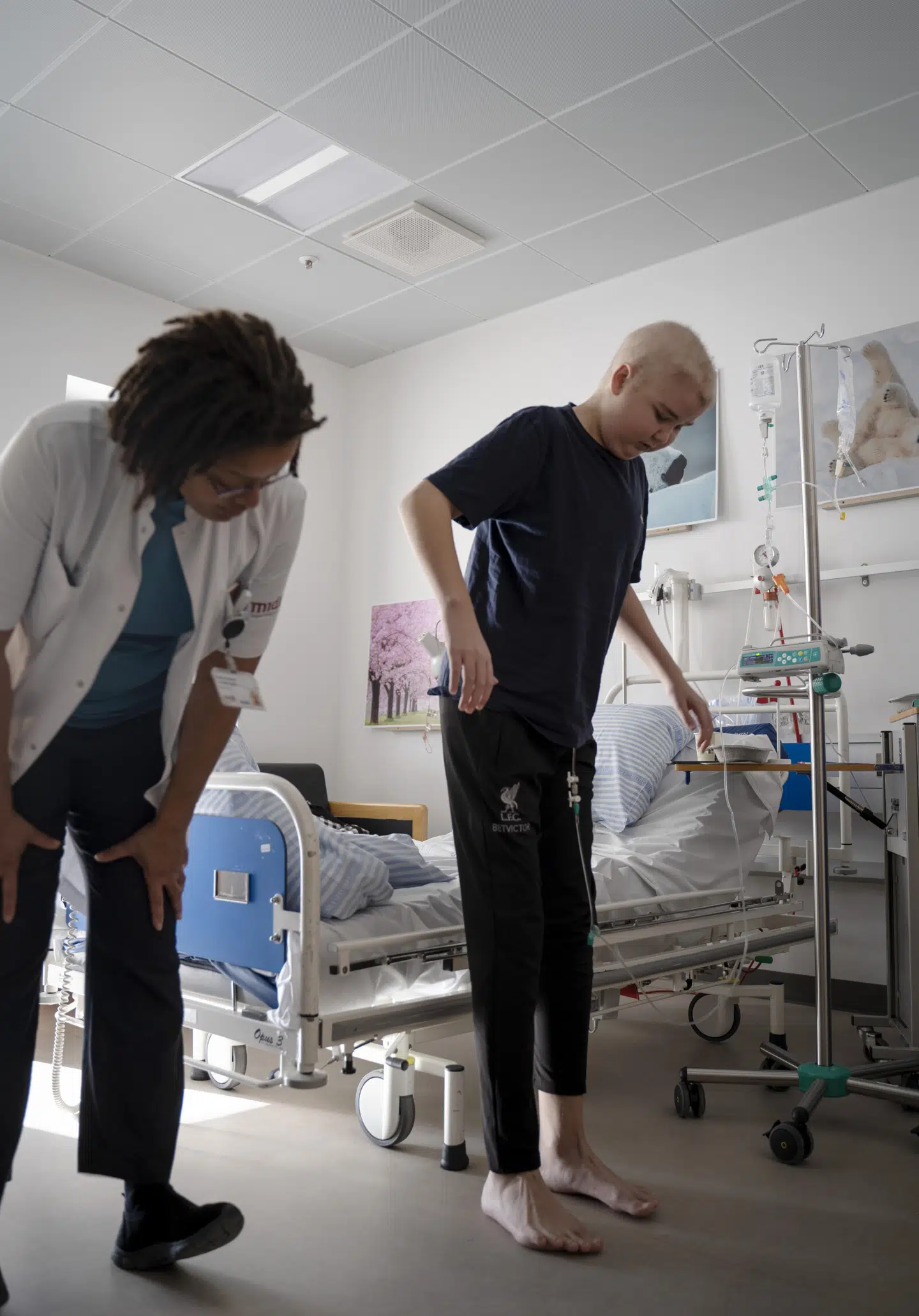 Oliver bor på enestue, da hans immunforsvar er svækket på grund af sygdommen. Her er en overlæge inde på stuen for at lave den daglige neurologiske undersøgelse på ham, inden dagens kemobehandling. Det indebærer blandt andet klappeøvelser, og at Oliver skal op at stå på tæerne. Det er et fremskridt, at han overhovedet kan stå op af sig selv. Foto: Sarah Christine Nørgaard