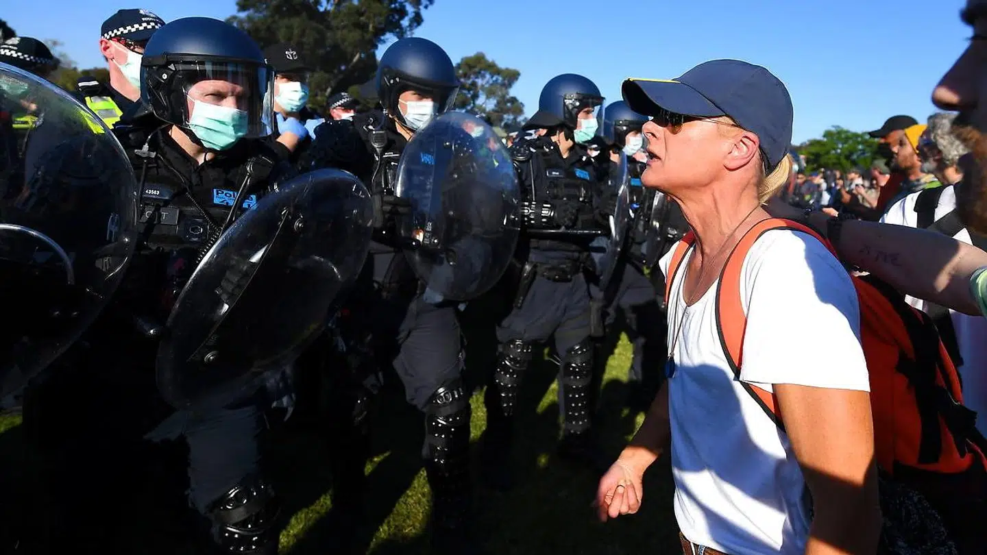 En demonstrant i Melbourne konfronterer kampklædt politi.