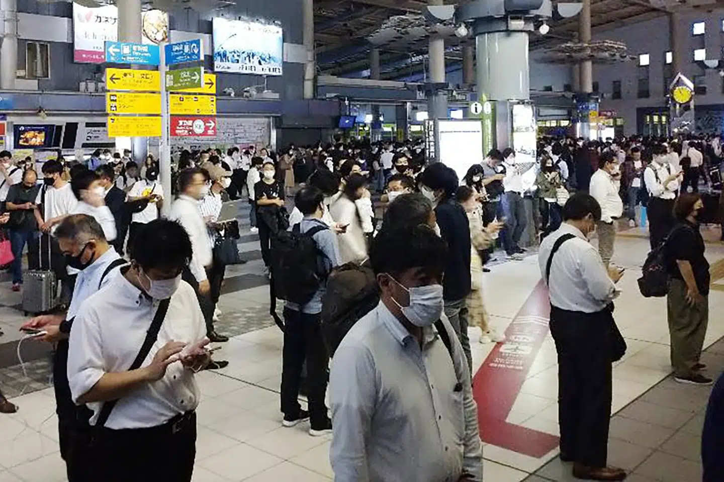 Passagerer ved indgangen til togstationen JR Shinagawa i Tokyo venter, mens togselskabet foretager et sikkerhedstjek efter et kraftigt jordskælv torsdag aften lokal tid. Skælvet betød, at de ellers notorisk rettidige højhastighedstog holdt midlertidigt stille. Uncredited/Ritzau Scanpix