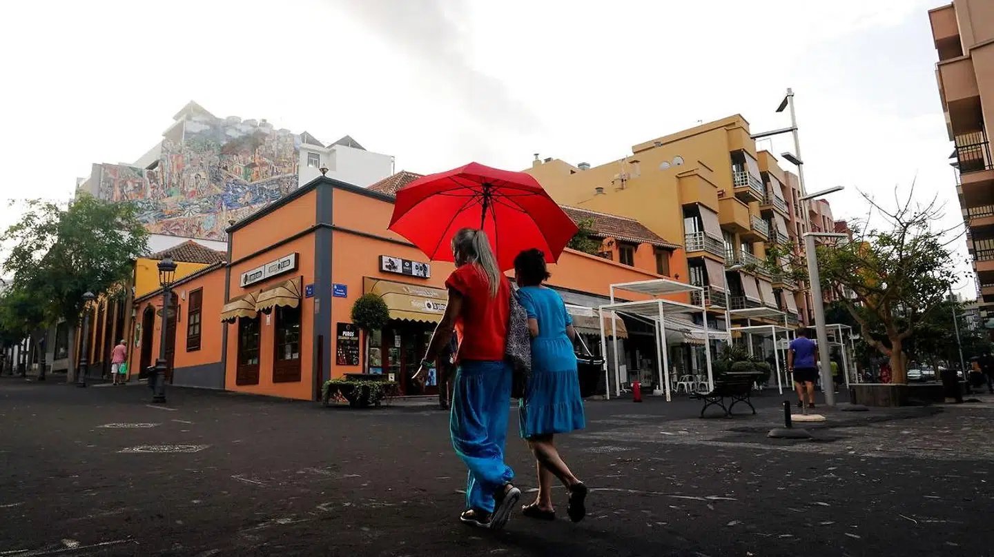 Folk går med paraply for at beskytte sig selv mod aske fra vulkanen på øen.