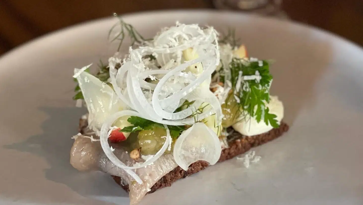 På en bund af rugbrød ligger silden med alt sit tilbehør.