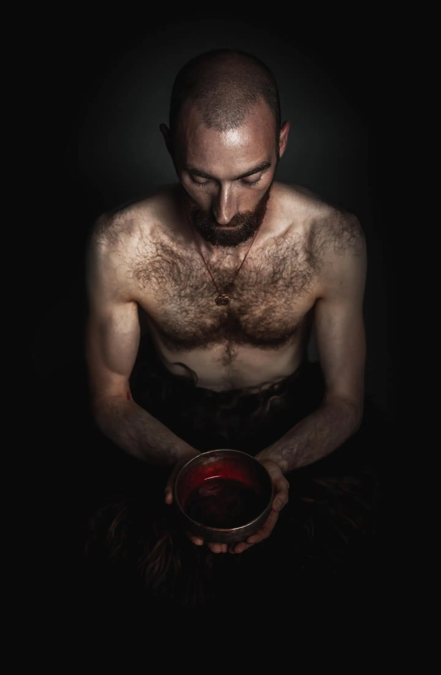 Tidligere præst Johan Christian Nord poserer her med en klangskål i hænderne fyldt med hans eget blod, som en bioanalytiker har tappet fra hans højre arm. Han knæler ikke, men sidder i lotus-meditationstilling for at udstråle »kontrol og værdighed frem for underkastelse«. Benene er dækket af et tæppe for at skabe en fornemmelse af noget dyrisk i forening med det menneskelige.