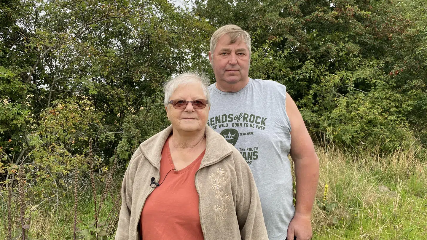 Inge og Ole ved motorvejen, der ligger 90 skridt fra deres hus.